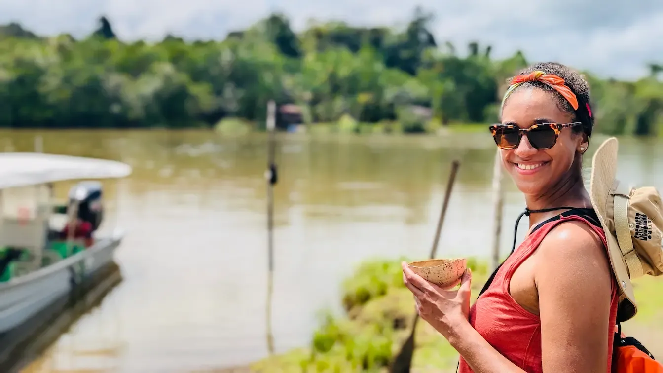 Woman drinking viche by the river during a Marimbea trip in Guapi